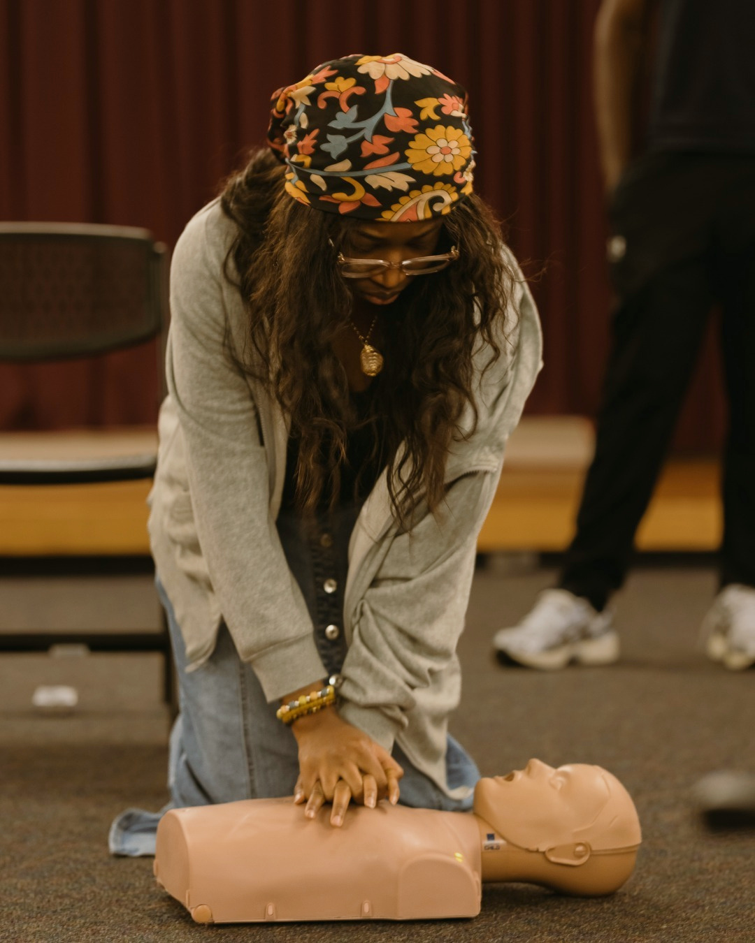 A participant practices CPR compressions on a manikin during a GoodWorks community class